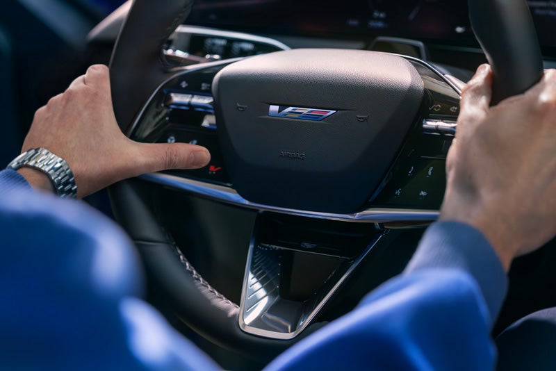 Close-up of a Man About to Press the V-Button on the 2026 OPTIQ-V Steering Wheel | Brotherton Cadillac in Renton WA