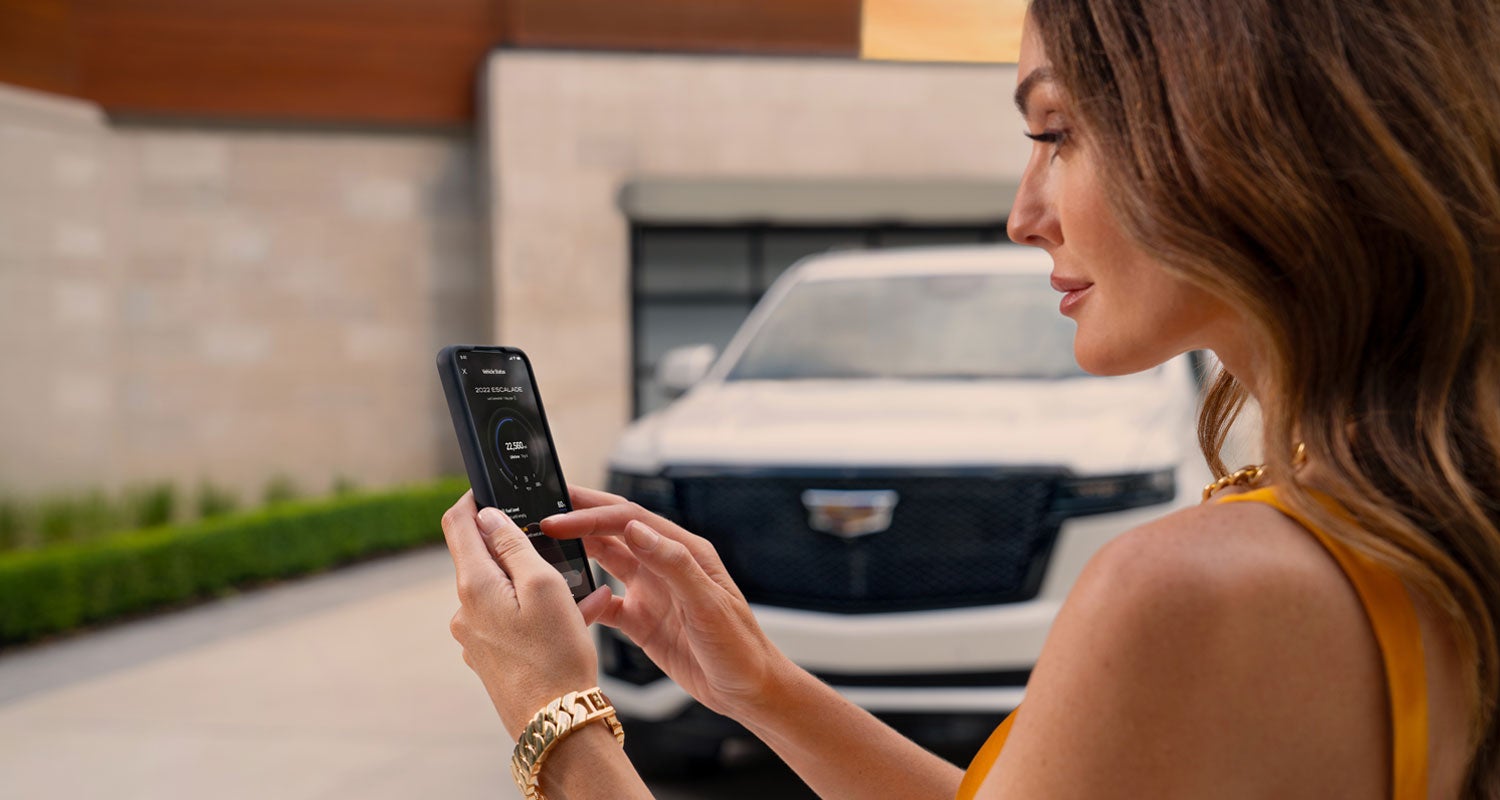 lady checking her mobile with a Cadillac vehicle background | Brotherton Cadillac in Renton WA